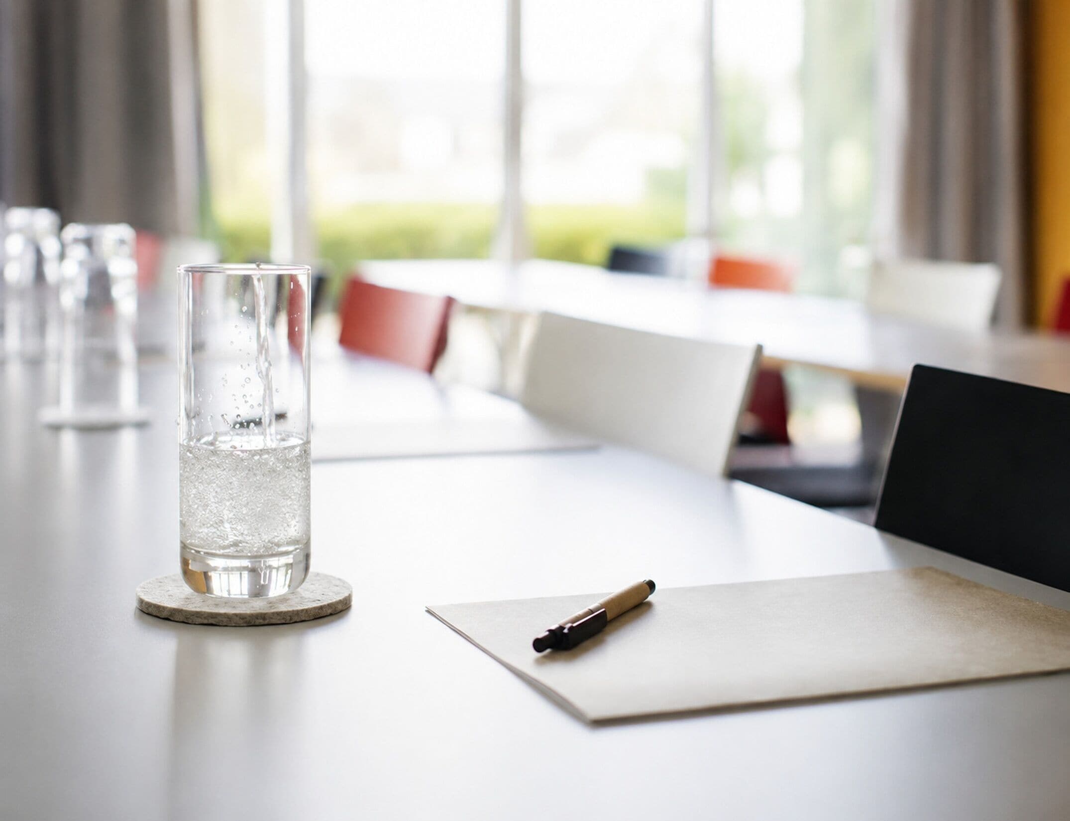 Una mesa de conferencias con un vaso de agua, un bolígrafo y documentos.