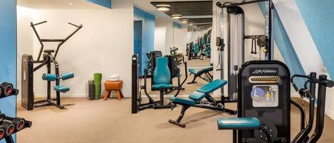 A gym with exercise equipment, mirrors, and a blue and white color scheme.