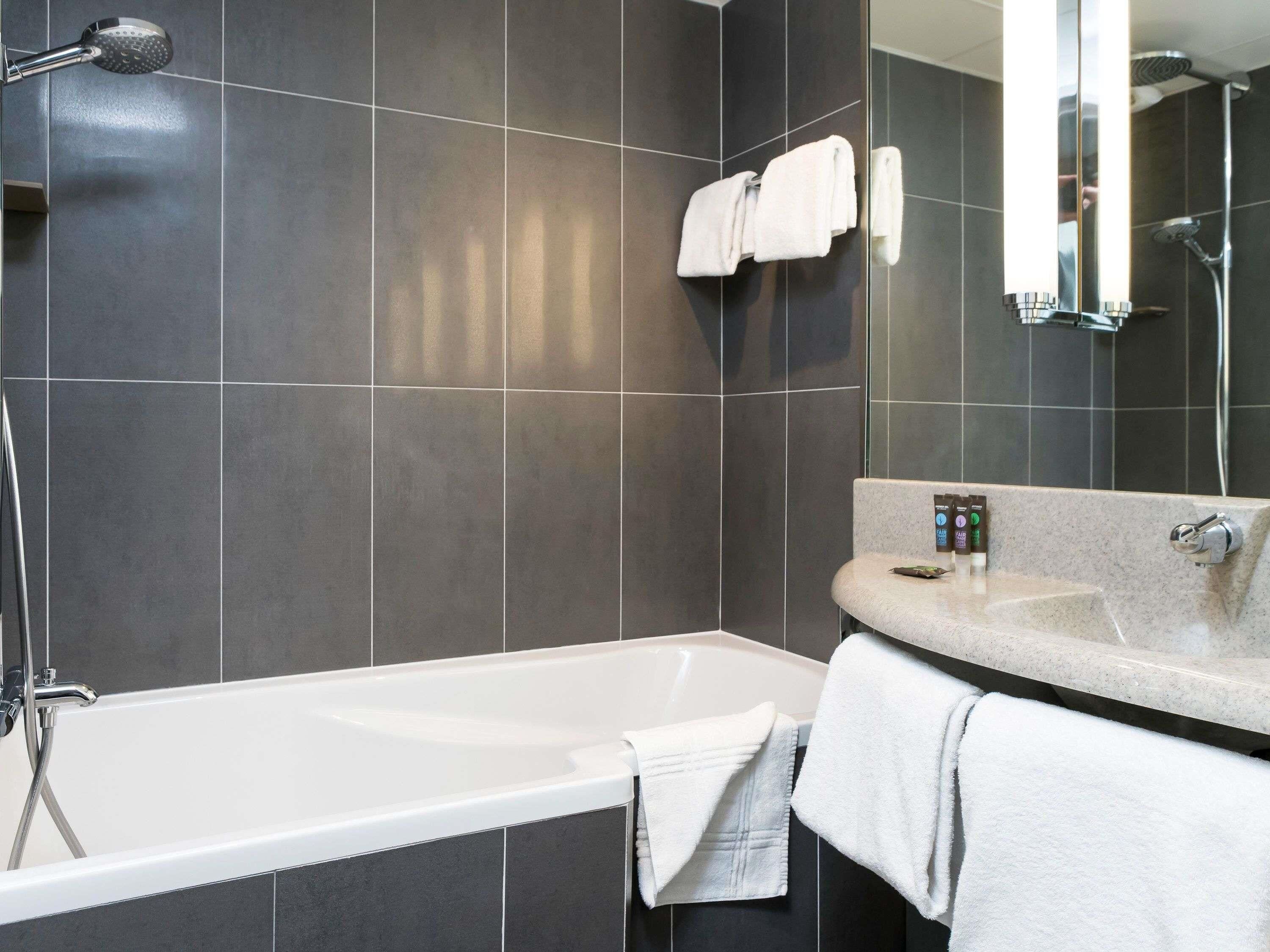 Une salle de bain moderne équipée d’une baignoire, d’une douche et d’un meuble-lavabo avec un miroir.