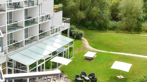 A modern multi-story building with outdoor seating and a glass conservatory.