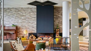 A modern lounge area with a fireplace, seating, and a piano.