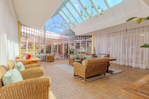 A spacious indoor area with wicker furniture, a glass ceiling, and a view of the outdoors. - Serra Alta Hotel (Sao Bento do Sul)