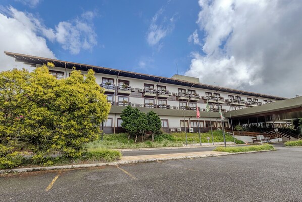 Un hotel de varios pisos con balcones, una entrada cubierta y un área de estacionamiento.