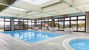 An indoor swimming pool with clear views of the surrounding landscape through large windows. - Serra Alta Hotel (Sao Bento do Sul)