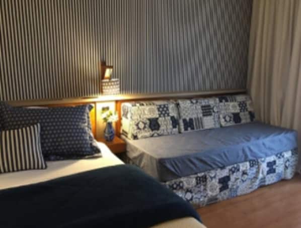 Una habitación de hotel con una cama, una mesita de noche y un papel tapiz estampado.