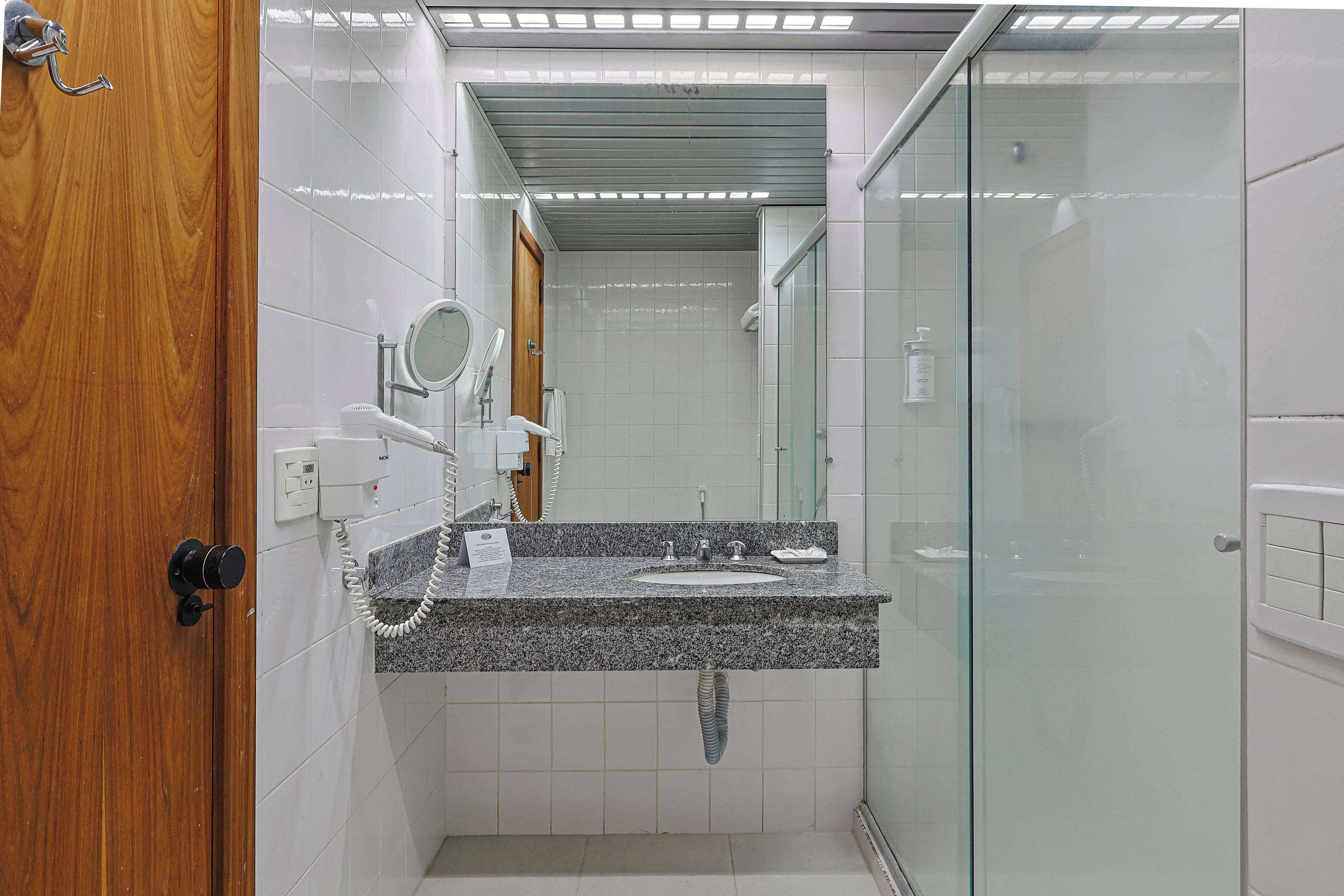 A bathroom with a granite countertop, a sink, a mirror, and a glass-enclosed shower.