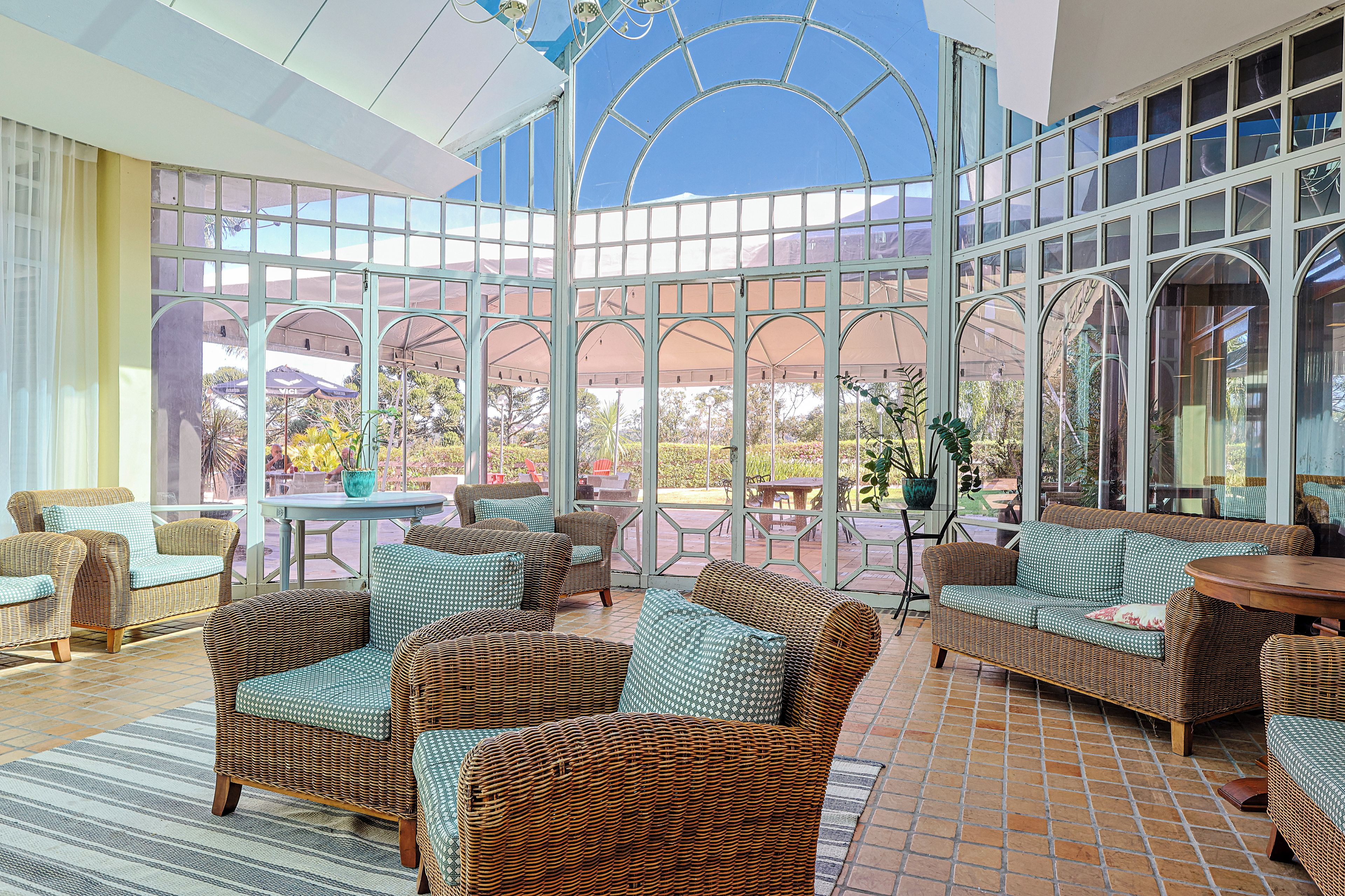 A conservatory with wicker furniture and a glass ceiling.