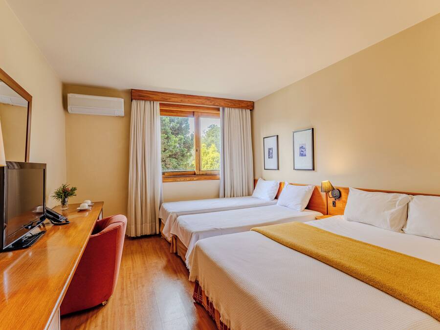 Habitación de hotel con dos camas, un escritorio con teléfono, una lámpara y una ventana con cortinas.