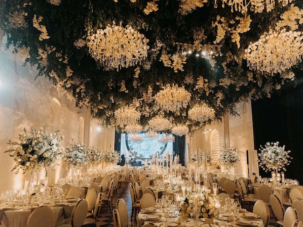 A banquet hall with tiered seating, chandeliers, and floral arrangements. - Sofitel Legend Santa Clara Cartagena (Cartagena)