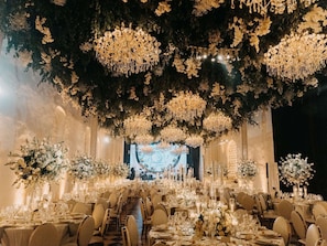 Une salle de banquet avec des gradins, des lustres et des décorations florales.
