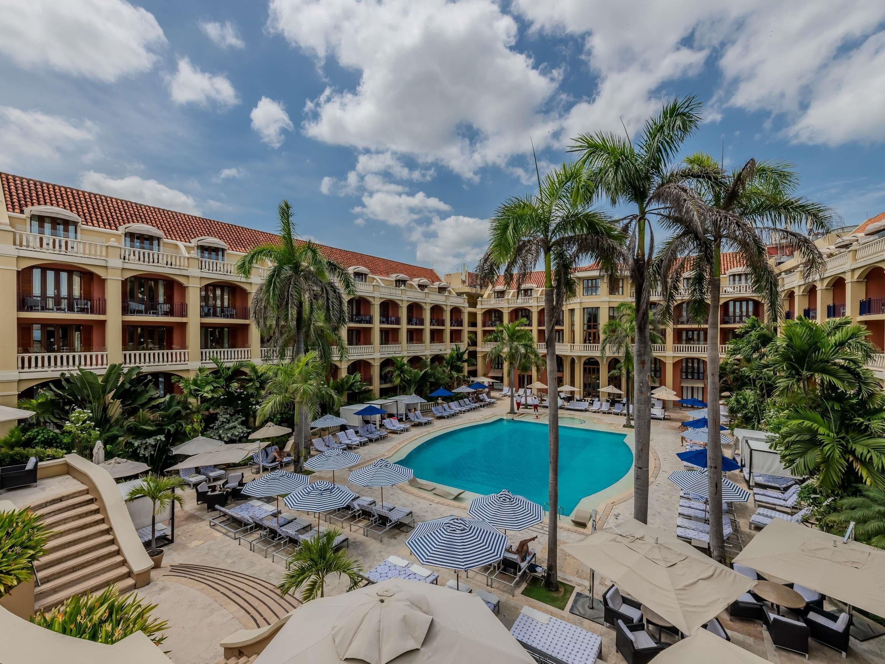 Un hotel con piscina, tumbonas y palmeras.