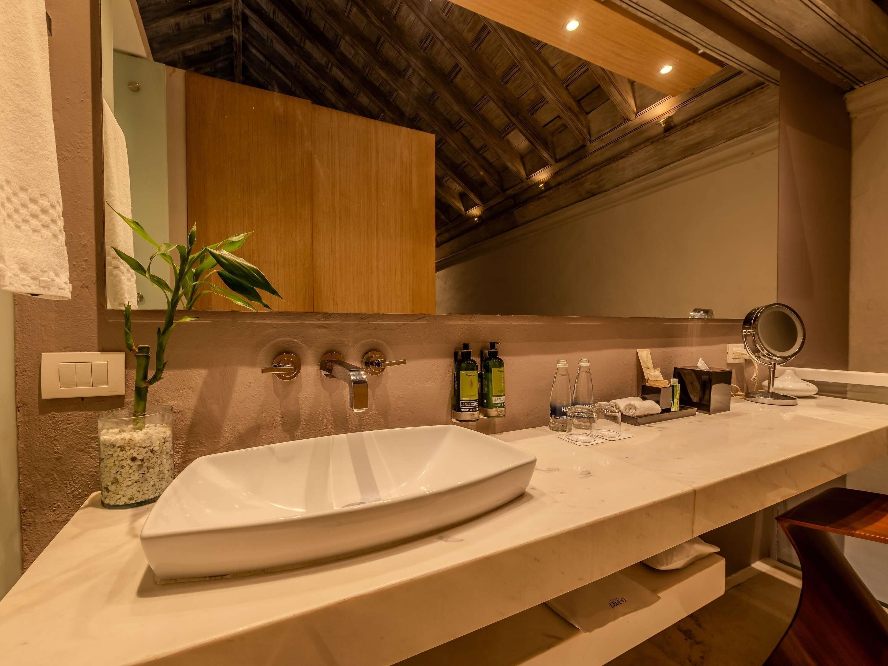 Un baño con un lavamanos grande de color blanco, un espejo y un techo de madera.
