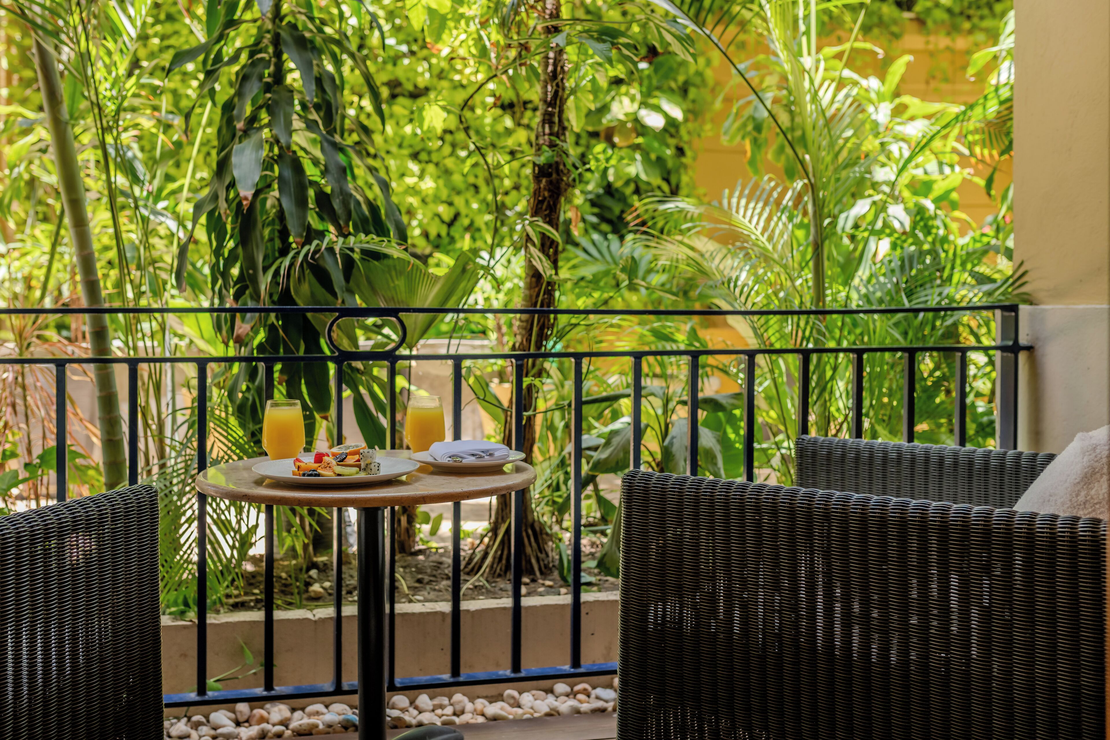 A balcony with wicker furniture, a small round table, and a drink.