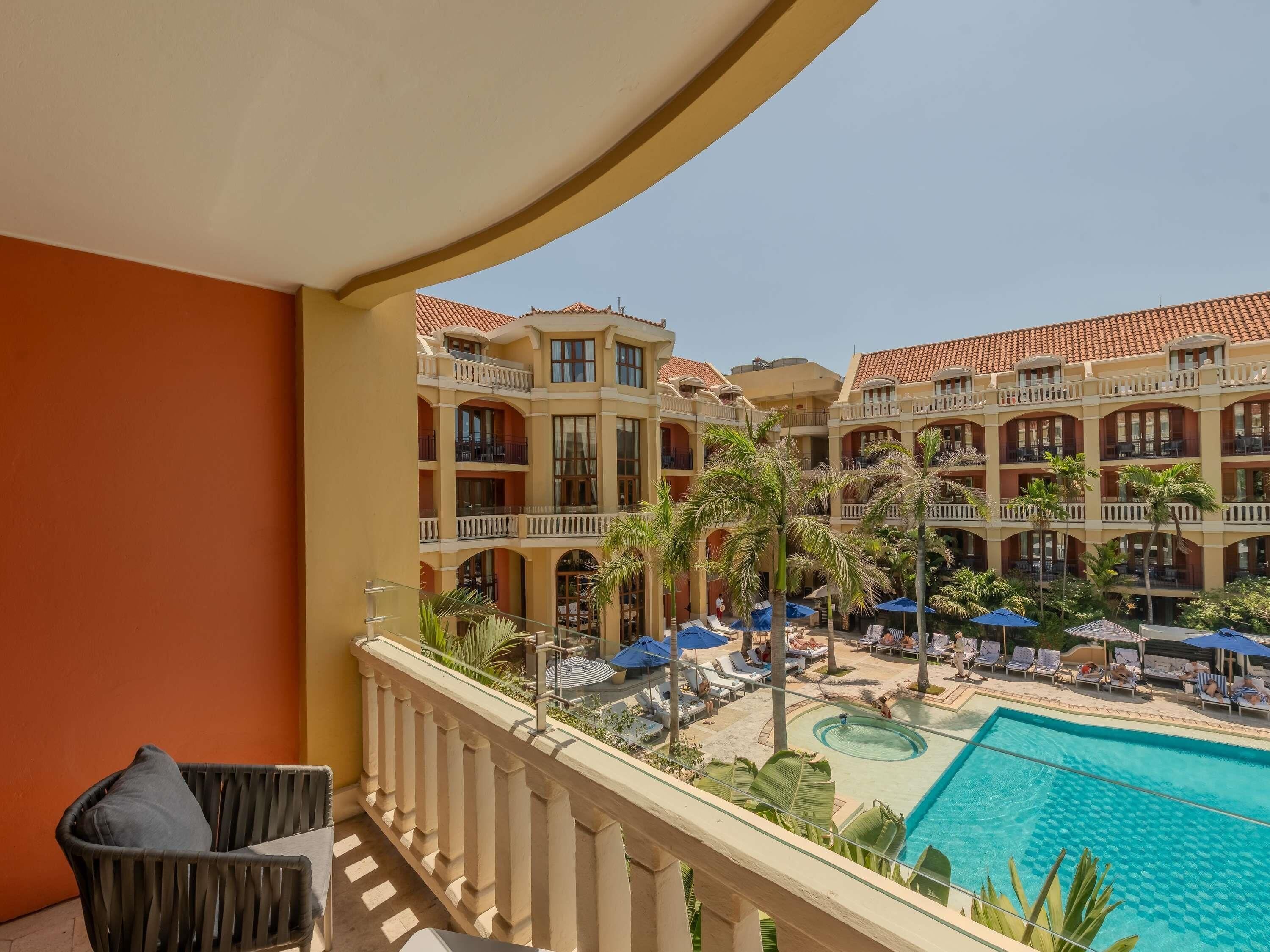 A hotel with a pool, multiple balconies, and palm trees.