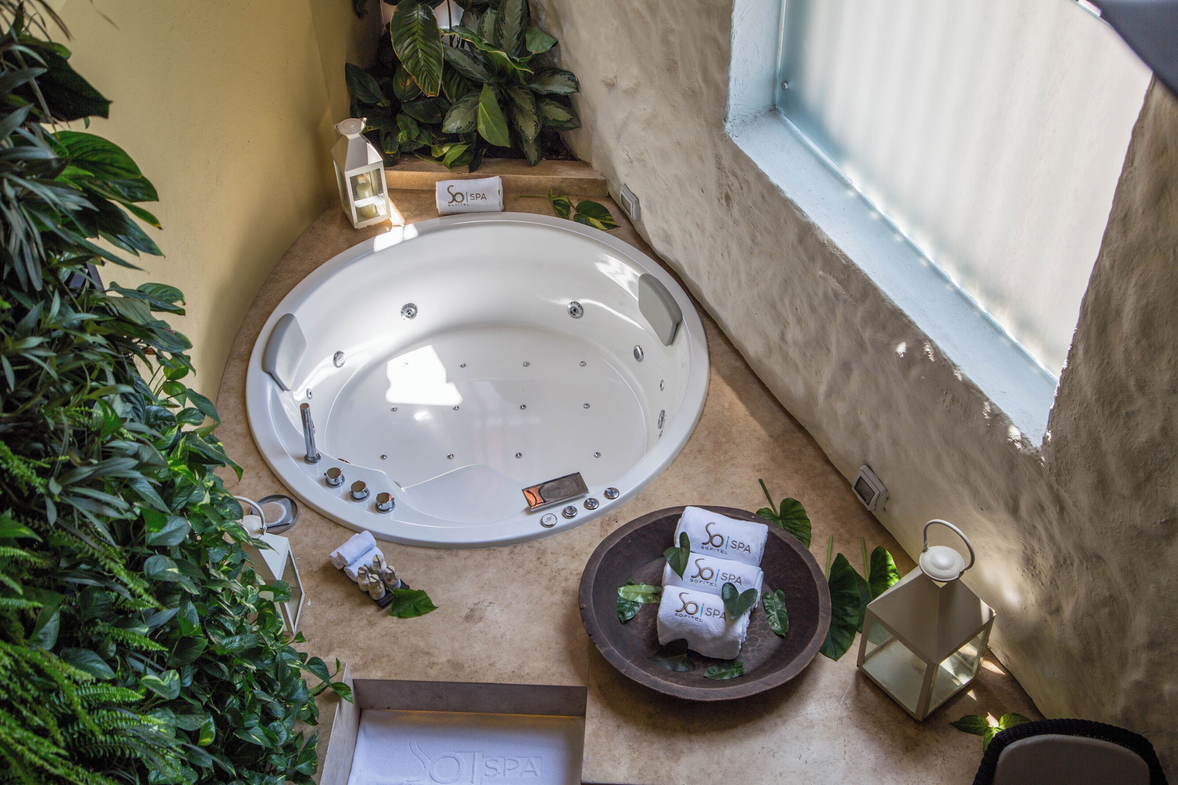 Ein Wellnessbereich mit Whirlpool, Pflanzen und Spa-Handtüchern.