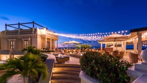 A hotel patio with outdoor seating, a bar, and a staircase leading to an upper level. - Sofitel Legend Santa Clara Cartagena (Cartagena)