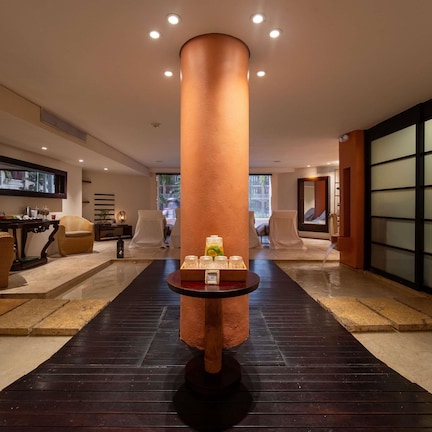 A hotel lobby with a central column, seating area, and a reception desk.
