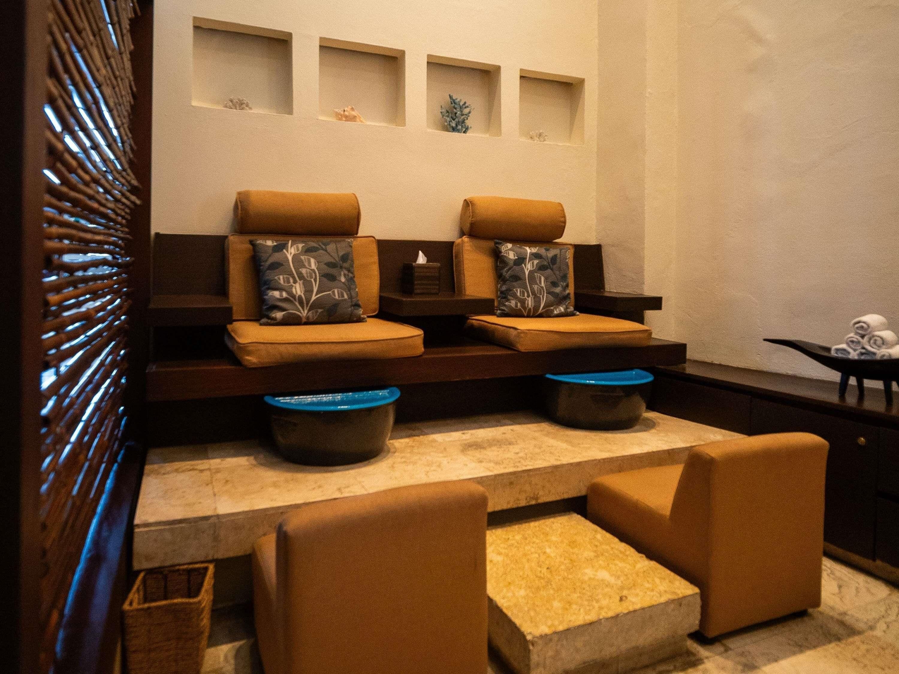 A spa area with two sofas, a small table, and a wall with three shelves.