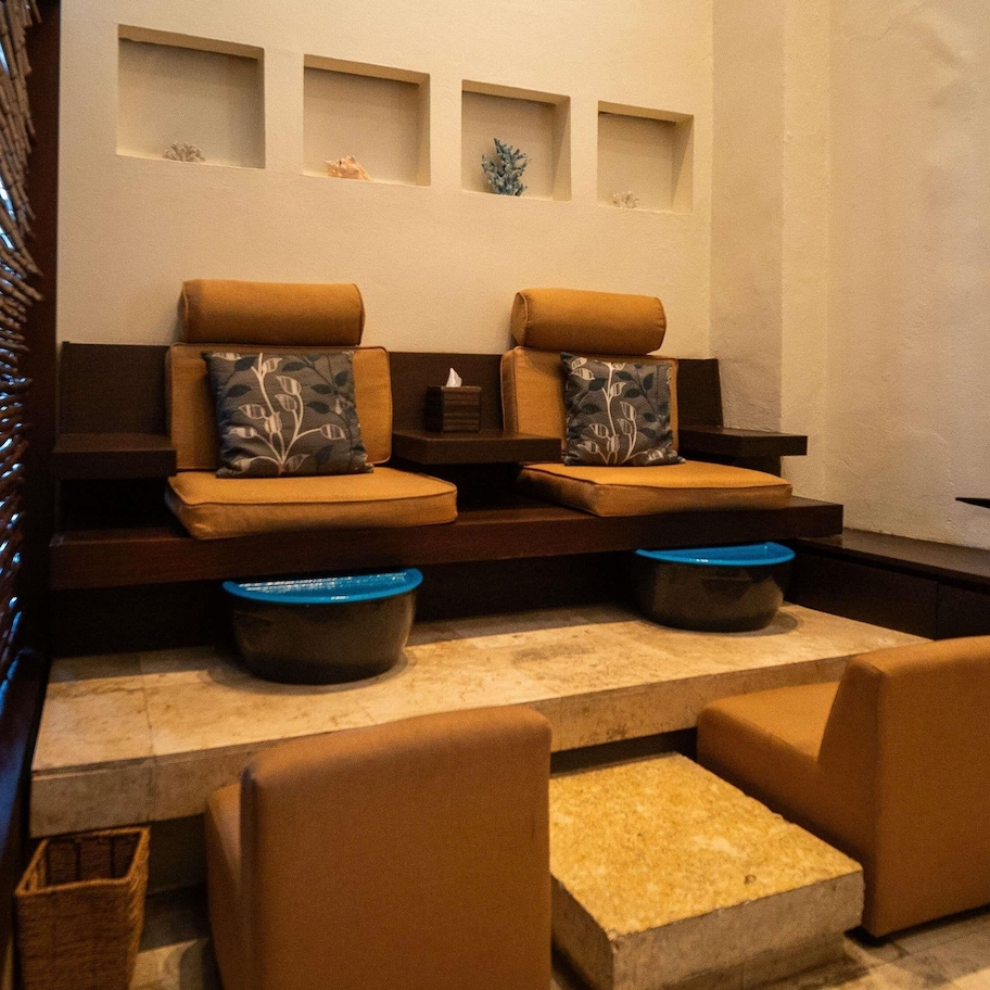 A spa area with two sofas, a small table, and a wall with three shelves.