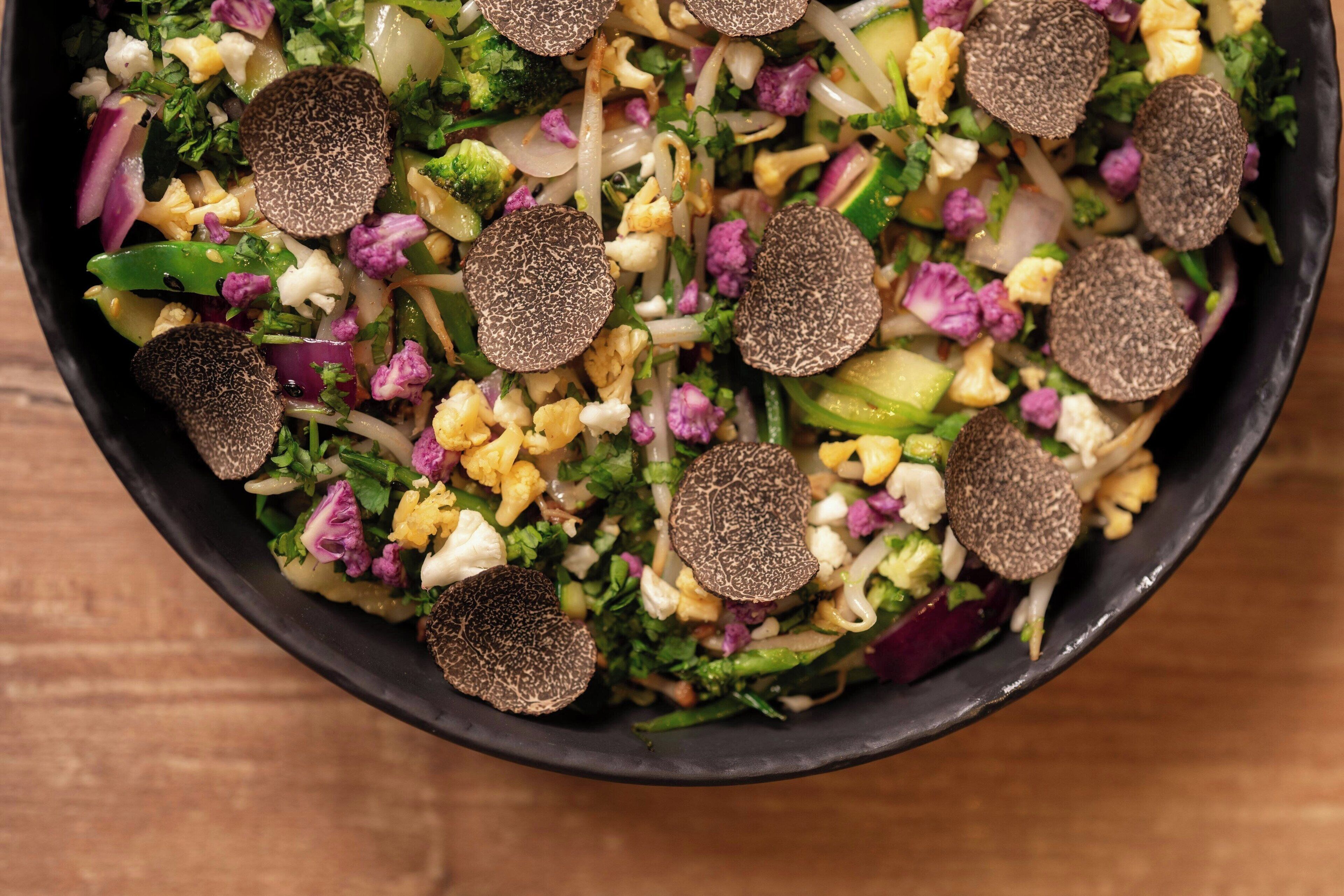 Een saladekom met diverse ingrediënten en truffels.