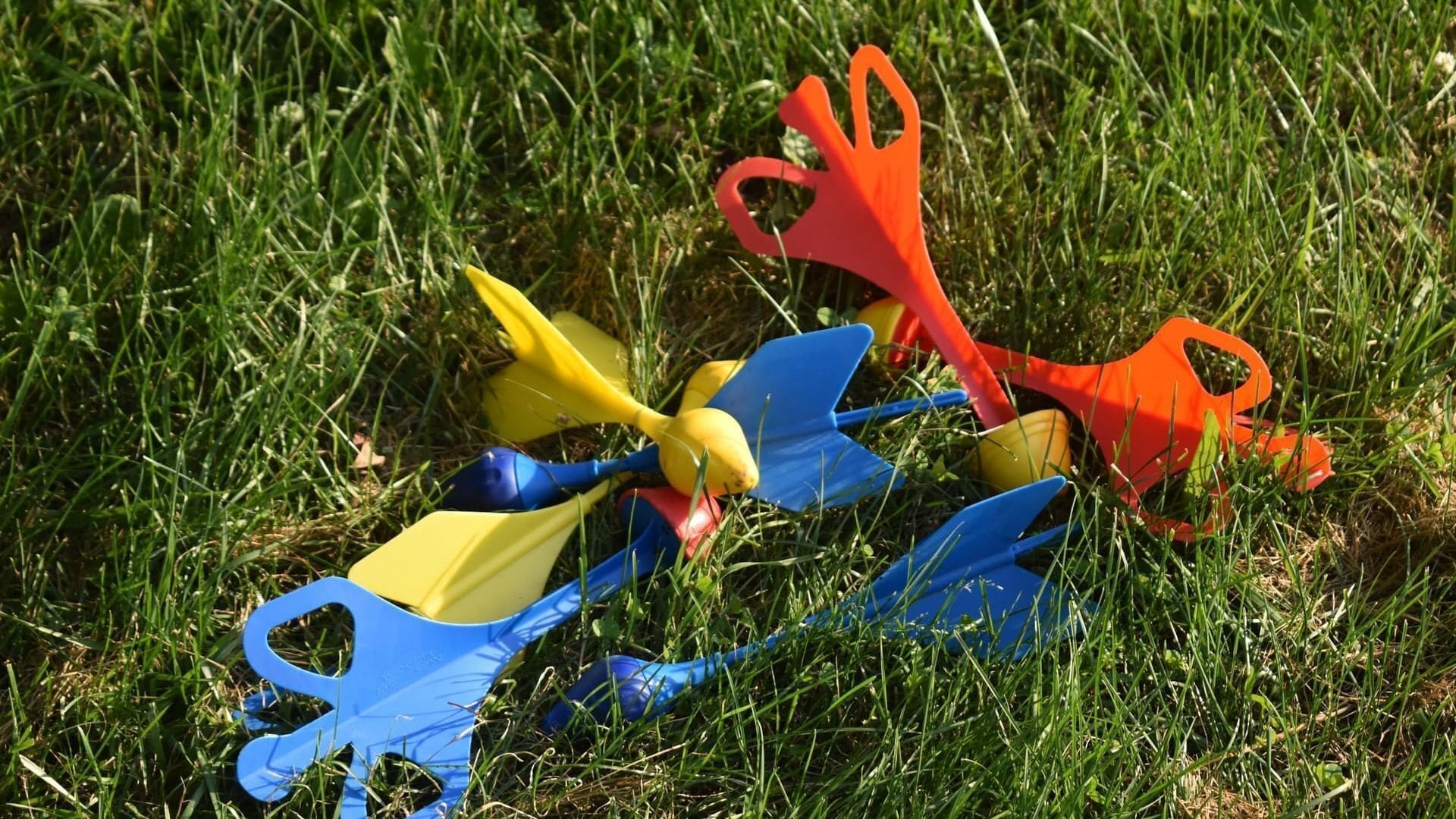 Una colección de juguetes de plástico de colores sobre césped.