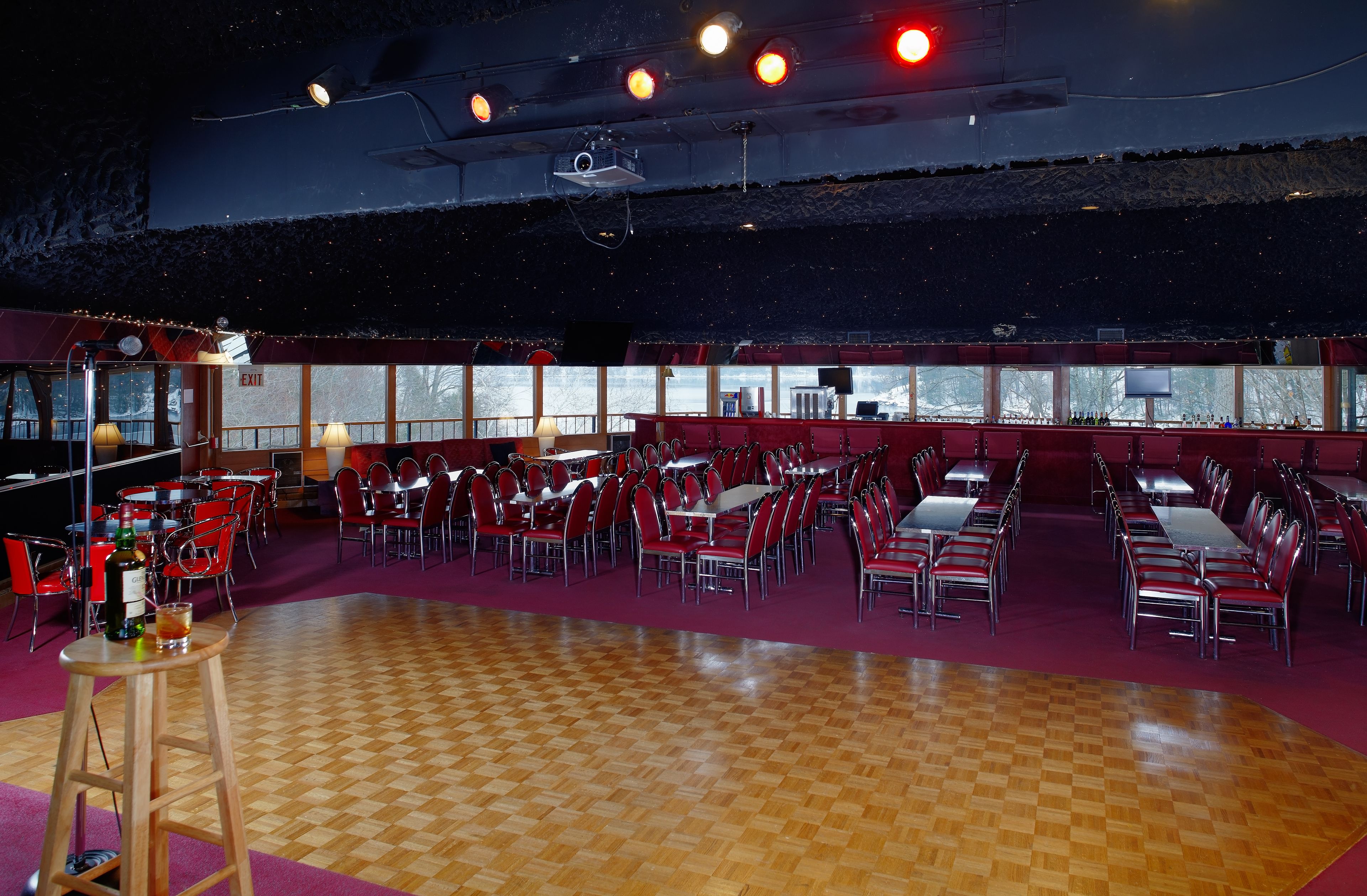 A spacious indoor dining area with high ceilings, large windows, and a checkered wooden floor.
