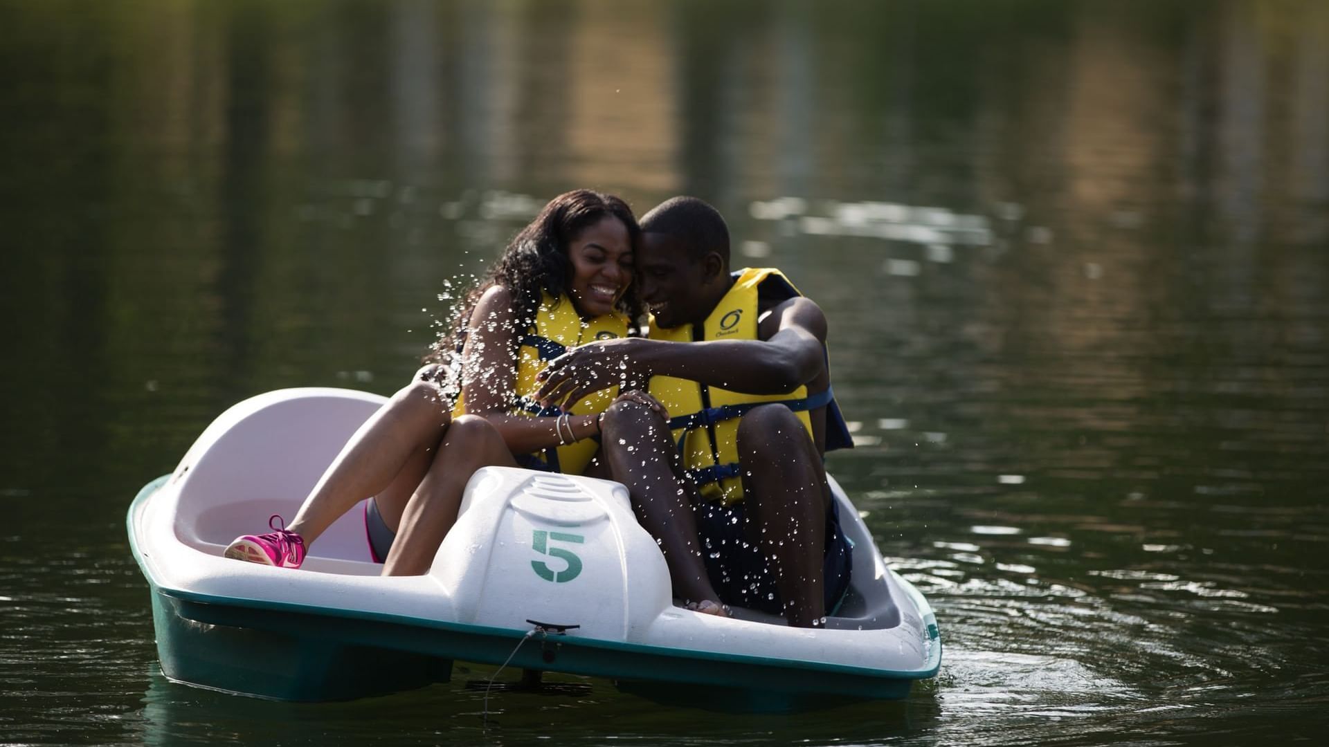 A couple in a small boat with a number 5 on it, wearing life jackets.