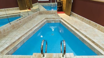 A swimming pool with clear blue water, tiled steps, and metal handrails.