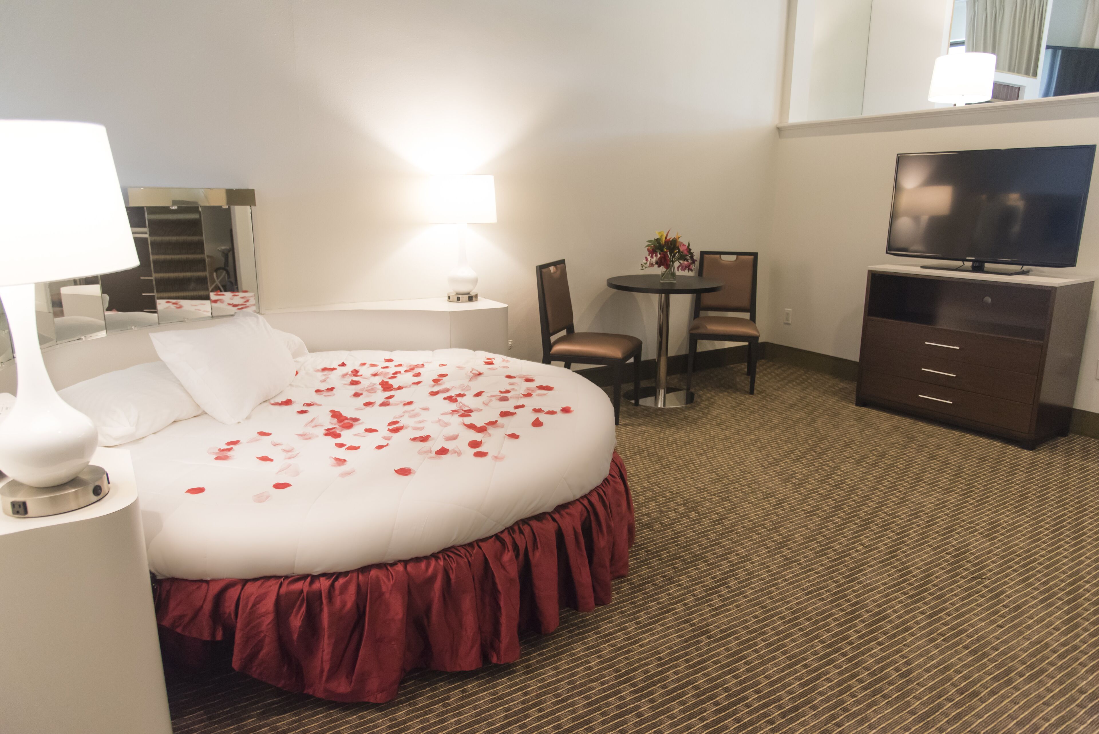 Une chambre d’hôtel avec un grand lit, un bureau, une chaise, une télévision et un miroir.