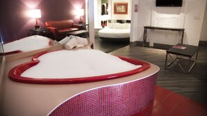 Una habitación de hotel con una bañera grande, un sofá, un escritorio y un televisor.
