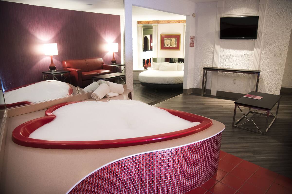 Une chambre d’hôtel avec une grande baignoire, un canapé, un bureau et une télévision.