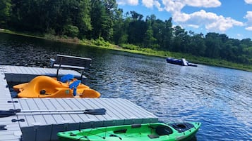 A dock with a kayak, a paddleboard, and a bench.