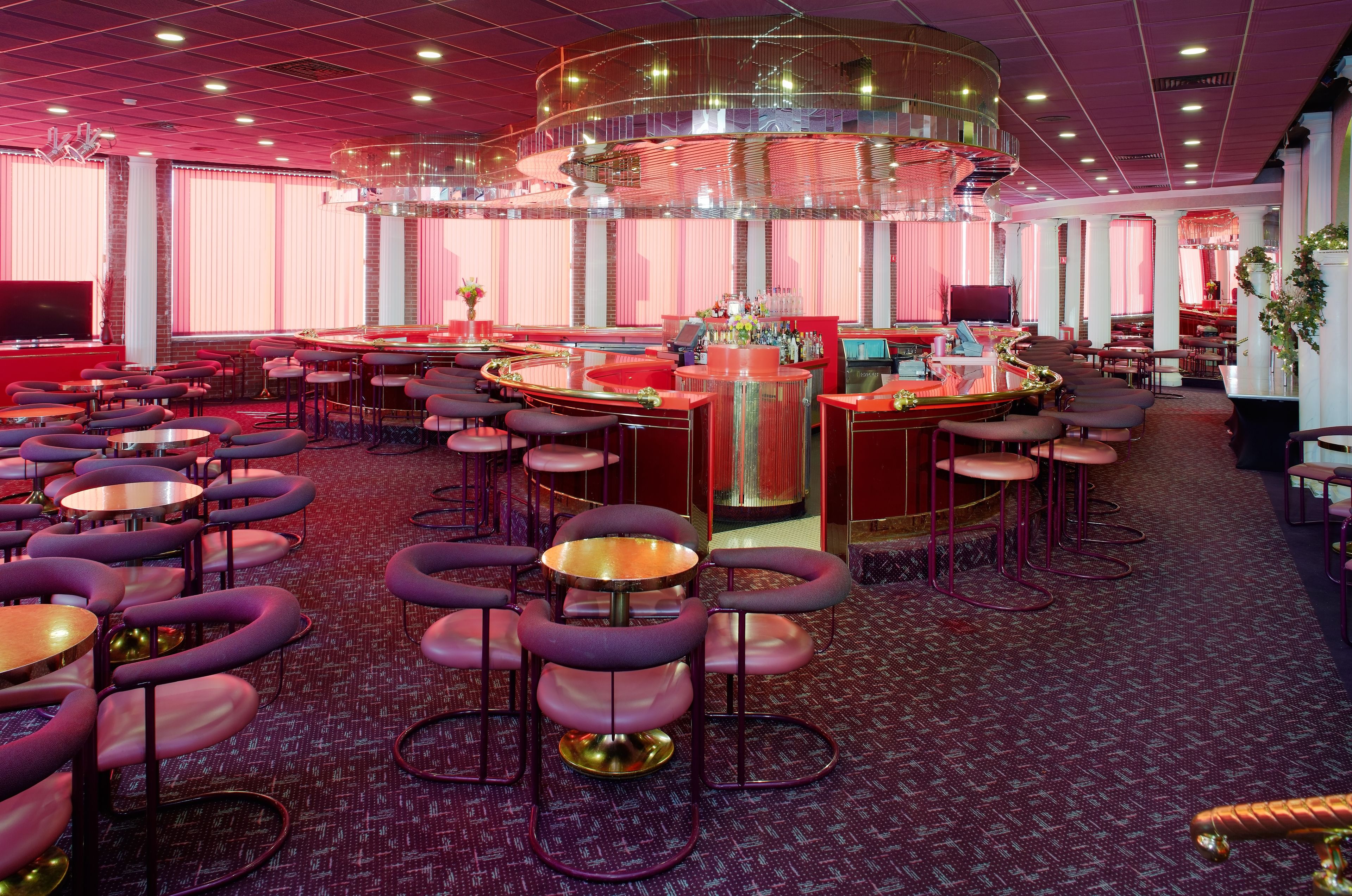 A spacious bar area with multiple seating options, including round tables and bar stools.