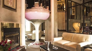 A modern lobby with a large, unique centerpiece, comfortable seating, a fireplace, and a glass-enclosed area.
