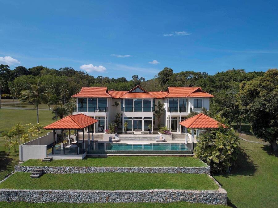 Een modern huis met twee verdiepingen, een zwembad, een overdekt terras en een verzorgd gazon.