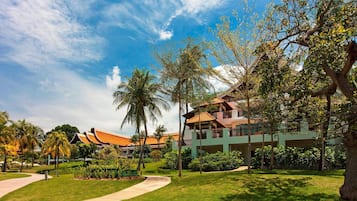 Stroll along the curved pathway to the resort's traditional building, surrounded by lush greenery and palm trees.