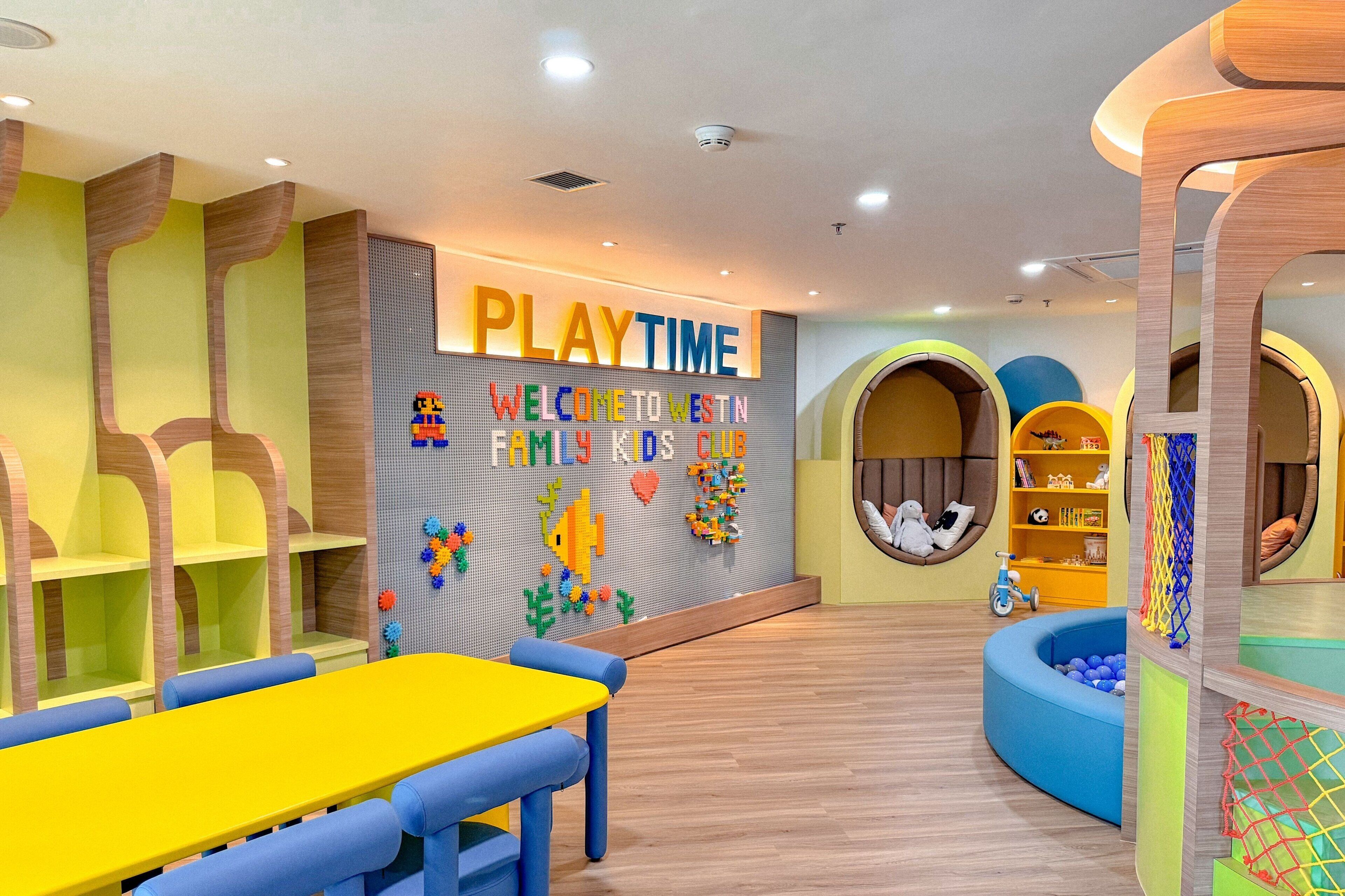 A children's play area with a 'PLAYTIME' sign, colorful play structures, and a blue ball pit.