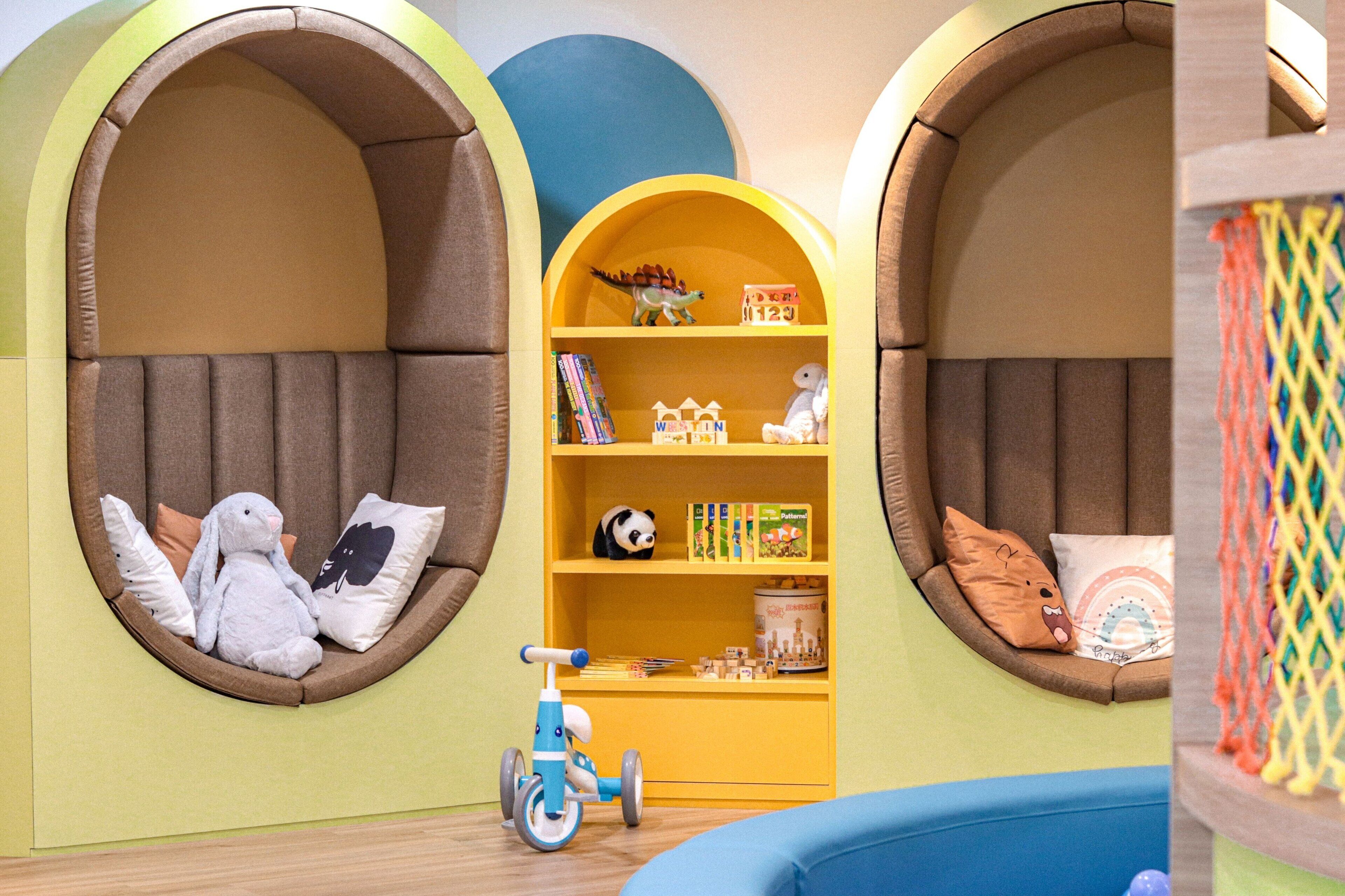 A children's play area with two arched seating areas, a small bookshelf, and a toy bicycle.
