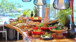 A buffet table with various dishes and a view of the ocean.