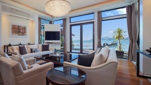 A modern living room with a large window, a chandelier, and a flat-screen TV.