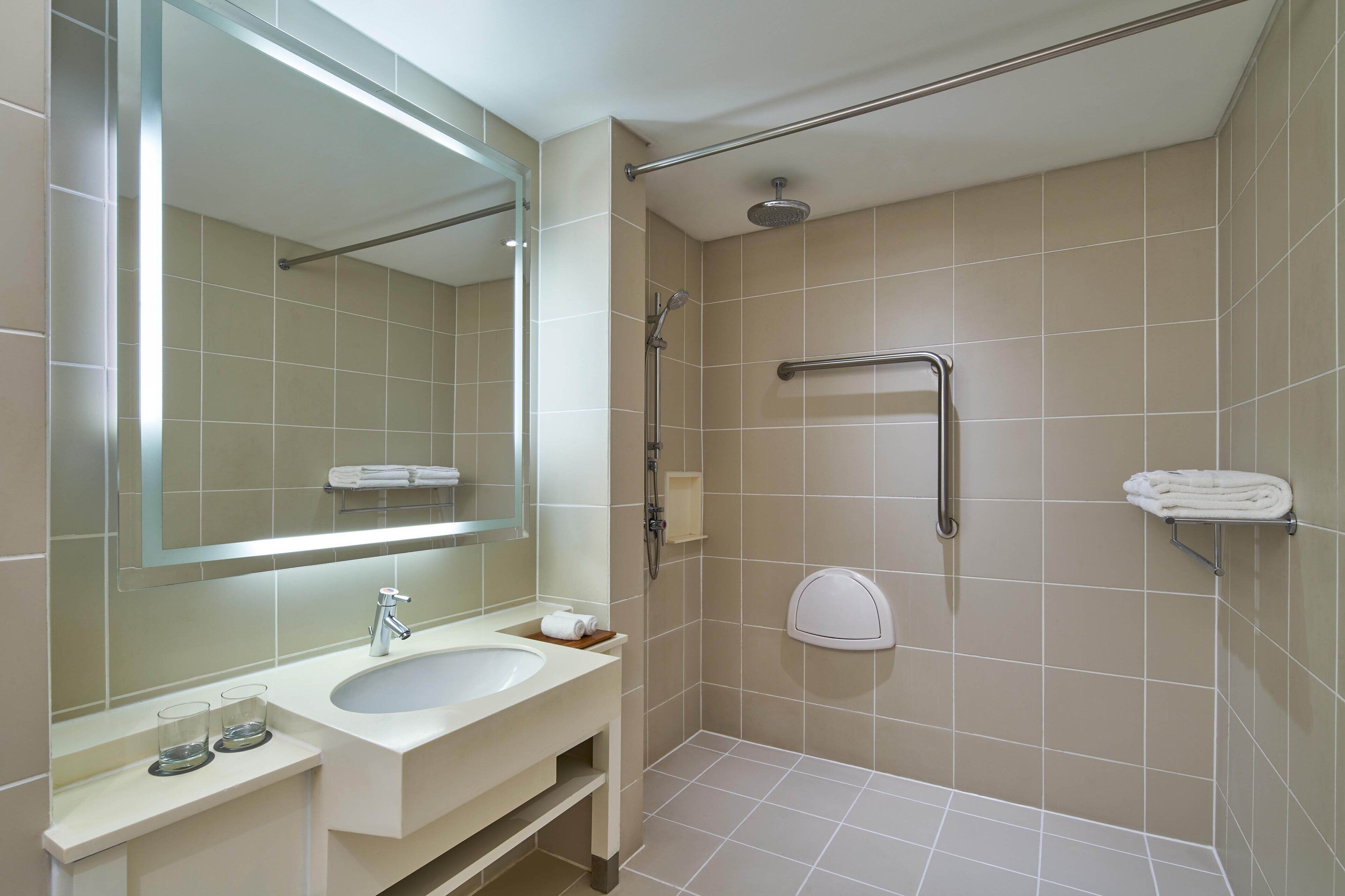 A modern bathroom with a sink, mirror, shower, and towel rack.