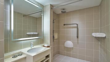 A modern bathroom with a sink, mirror, shower, and towel rack.