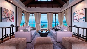 A spacious living room with a large window offering a view of the sea, two sofas, a coffee table, and artwork on the walls.