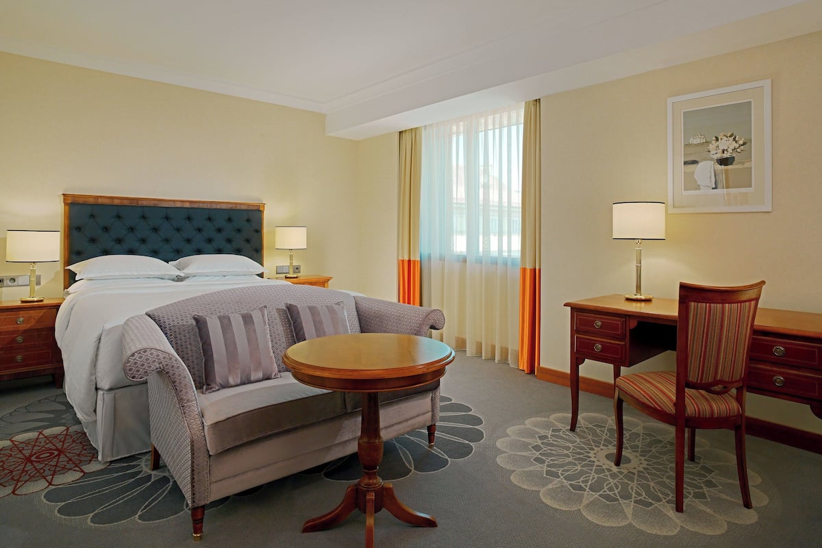 A hotel room with a bed, a sofa, a desk, and a chair.