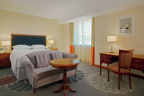 Relax in a cozy space with a large bed, sofa, and wooden desk.