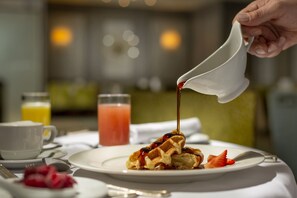 Waffles are served with a glass of orange juice and a cup of coffee.