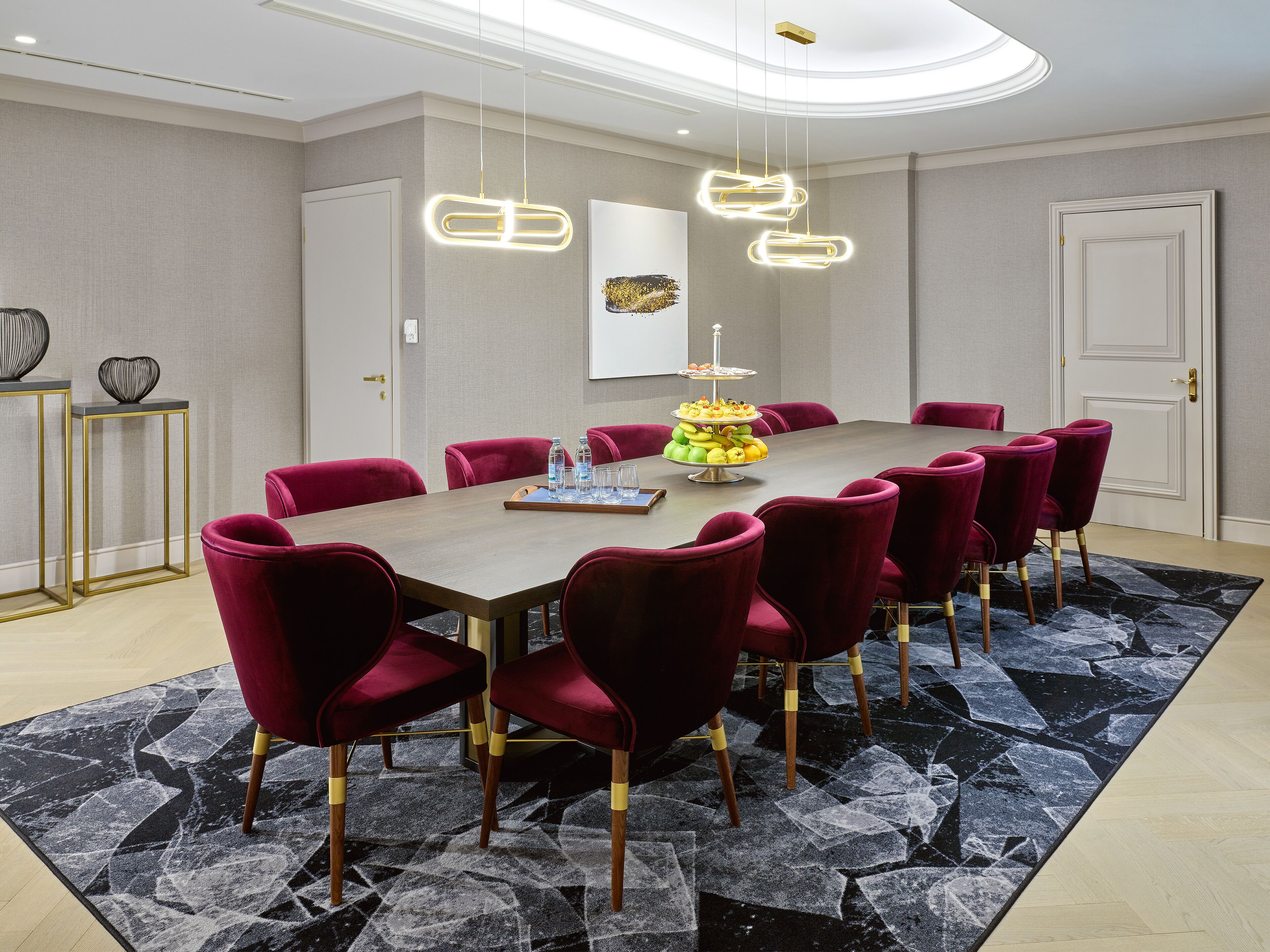 A conference room with a long table, red chairs, and a modern chandelier.