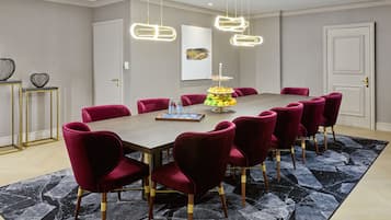 A conference room with a long table, red chairs, and a modern chandelier.