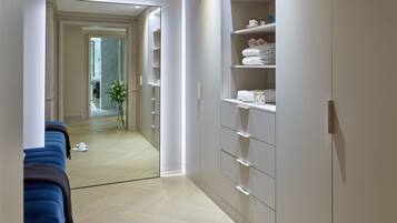A modern hotel room with a large wardrobe, a blue sofa, and a hallway leading to another room.