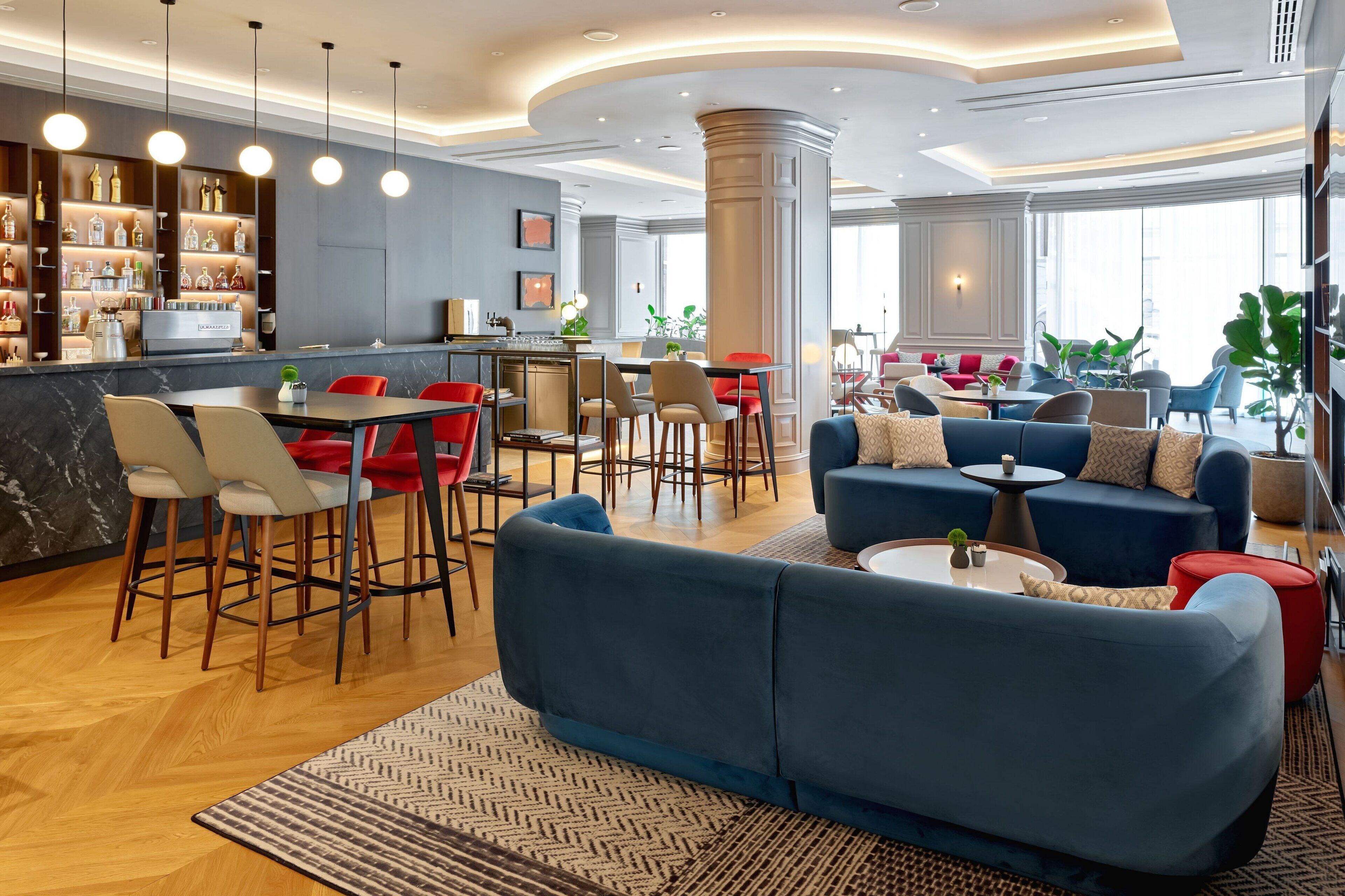 A modern hotel lobby with a bar area, seating arrangements, and a large window providing natural light.